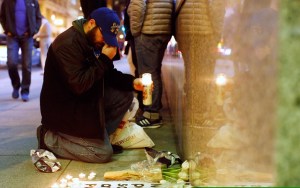 A man gestures as he places a candle at a makeshift memorial outside the Consulate General of France to pay tribute to the victims of the terror attack in Paris, in San Francisco, California November 13, 2015. REUTERS/Stephen Lam - RTS6XJZ